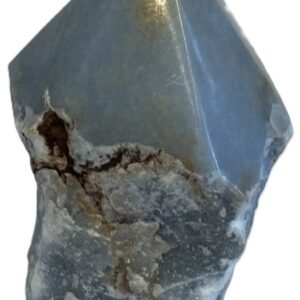 Natural rough angelite freeform crystal with unpolished sides and a smooth polished blue point standing on a white background